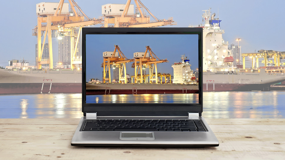 logistic business concept idea, laptop on wooden table with port warehouse and cargo ship background